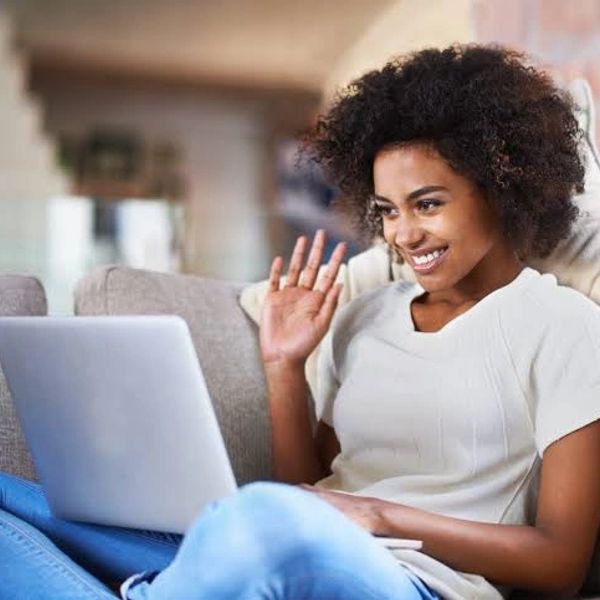 Woman waving while video chatting on laptop.