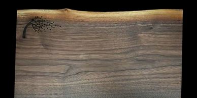 Live edge walnut board with engraved tree on top left coner