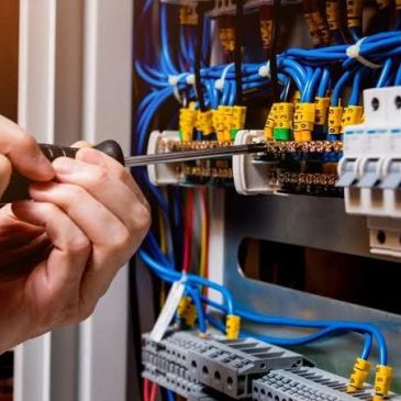 Mano ajustando componentes eléctricos con destornillador.