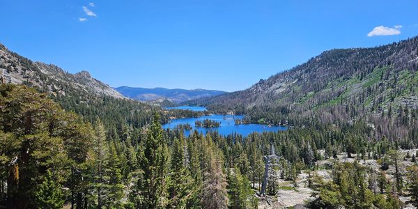 A view of Echo Lakes in California. The lakes lie in a forested basin w/a bright blue sky overhead