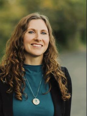 Smiling woman with curly hair outdoors.