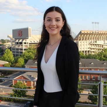 Young woman smiling with stadium in background.