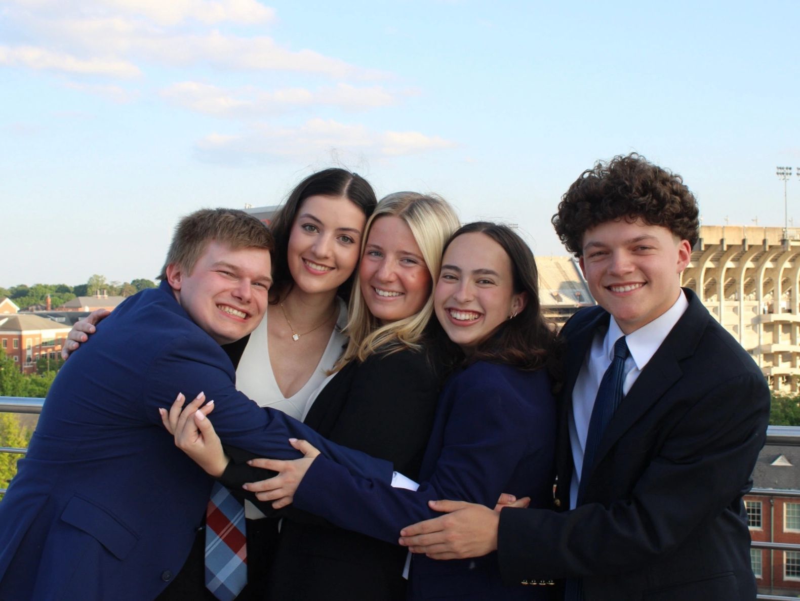 Group of friends joyfully hugging outdoors.