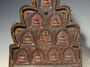 An ancient carved wooden artifact with multiple small Buddha figures.