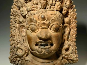 Ancient stone sculpture of a fierce deity with intricate detailing.
