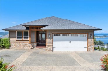 Modern single-story house with garage and water view.