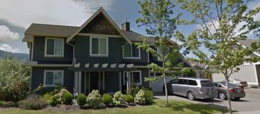 Two-story house with a driveway and parked cars.
