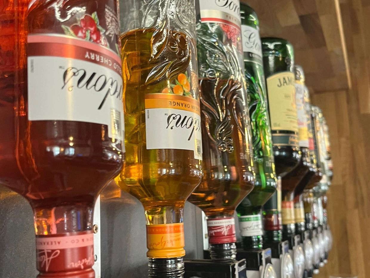 Rows of upside-down liquor bottles on a bar dispenser.