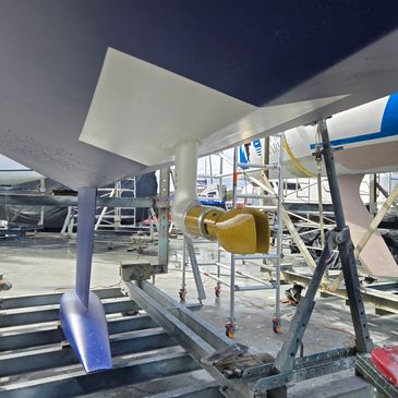 Close-up of a boat's underwater propeller and rudder system on a dock.