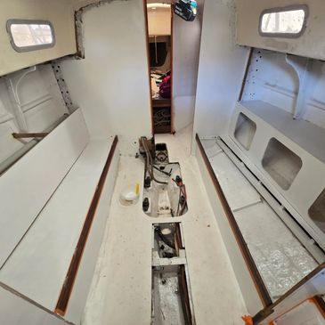 Interior of a boat cabin under renovation with exposed floor compartments.