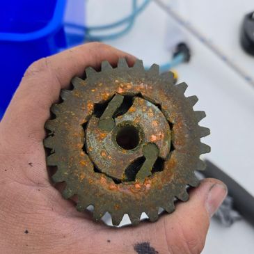 Rusty metal gear held in a person's hand.