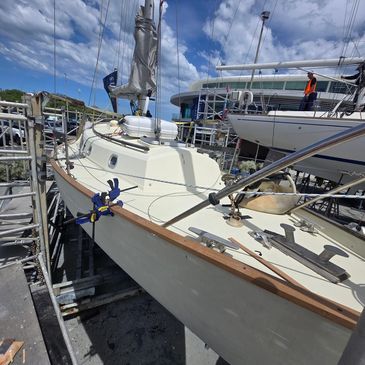 Sailboat docked on dry land under a blue sky with scattered clouds.