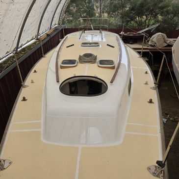 A beige and white sailboat deck stored indoors under a canopy.