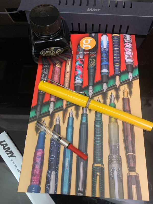 Yellow fountain pen, ink bottle, and colorful pen brochure.