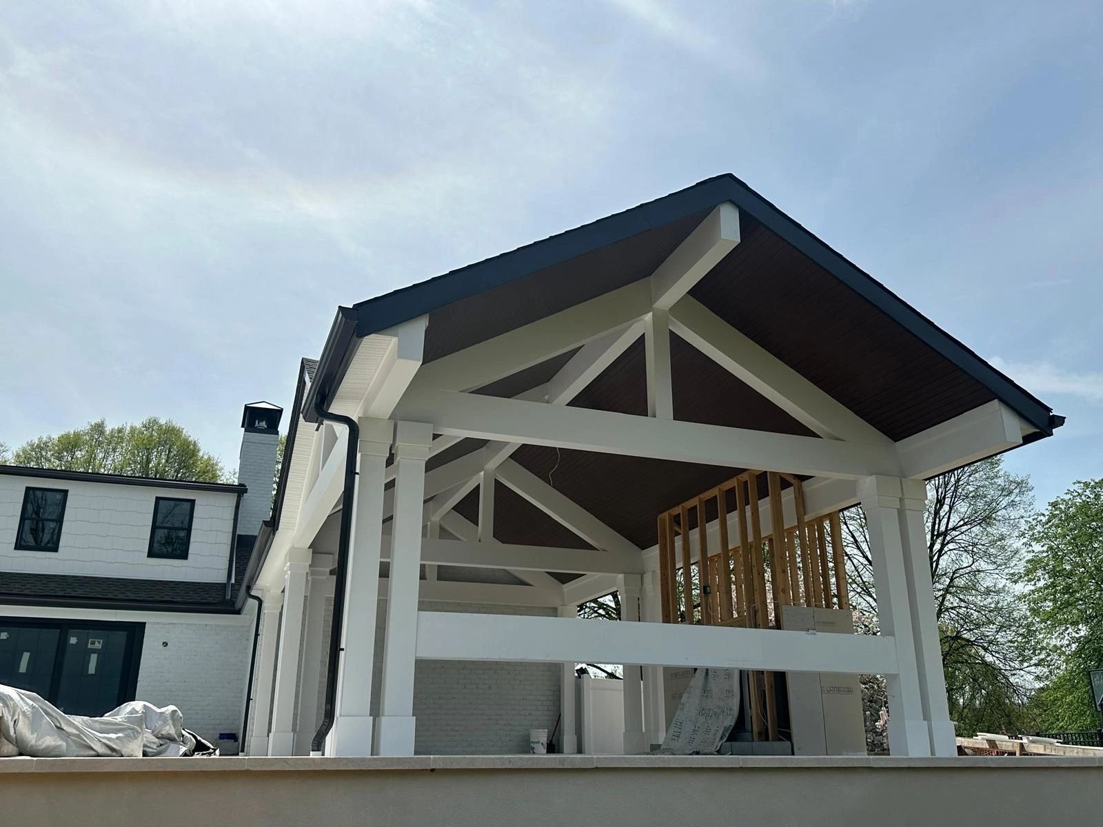 Modern house with a white porch and black roof under clear sky.