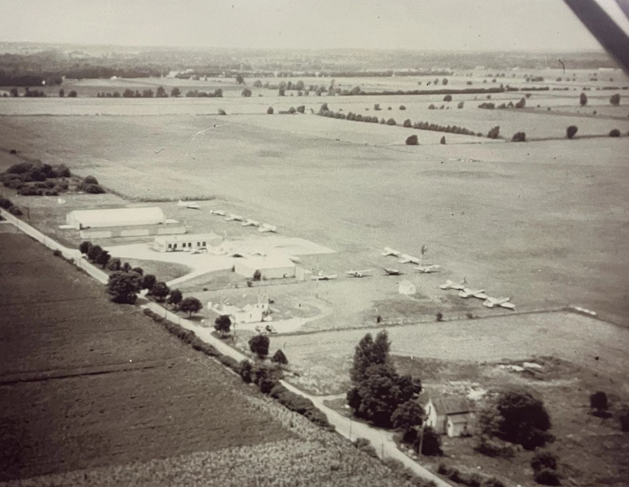 Aerial view of a rural airfield with small planes and surrounding farmland.