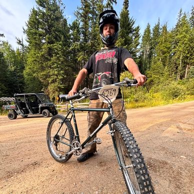 Person with helmet posing with mountain bike on dirt path.