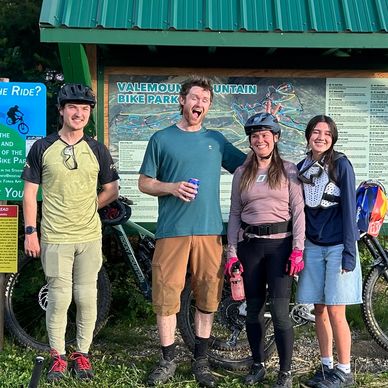 Group of mountain bikers posing by the Valemount Bike Park sign.