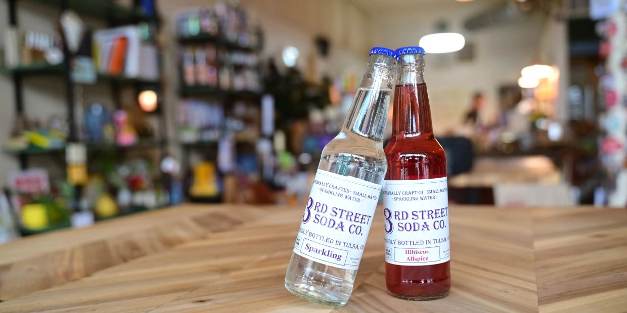 Two glass soda bottles on a wooden table.