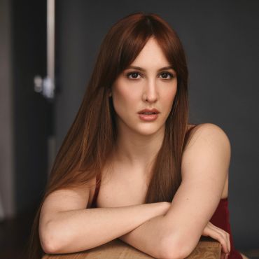 Mujer con cabello largo y expresión seria.