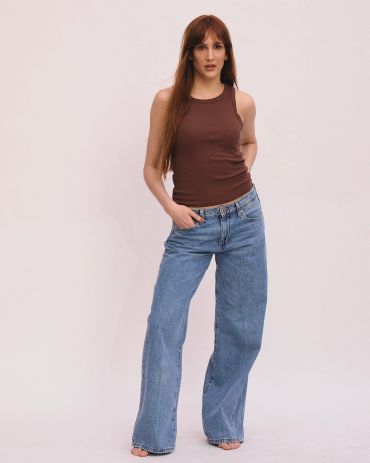 Mujer con camisola marrón y jeans acampanados.