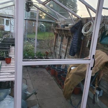 View inside a greenhouse with gardening tools and pots.