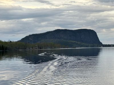 Serene lake with a mountainous backdrop under a cloudy sky.