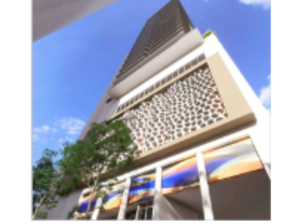 Looking up at a modern skyscraper with decorative facade and blue sky.
