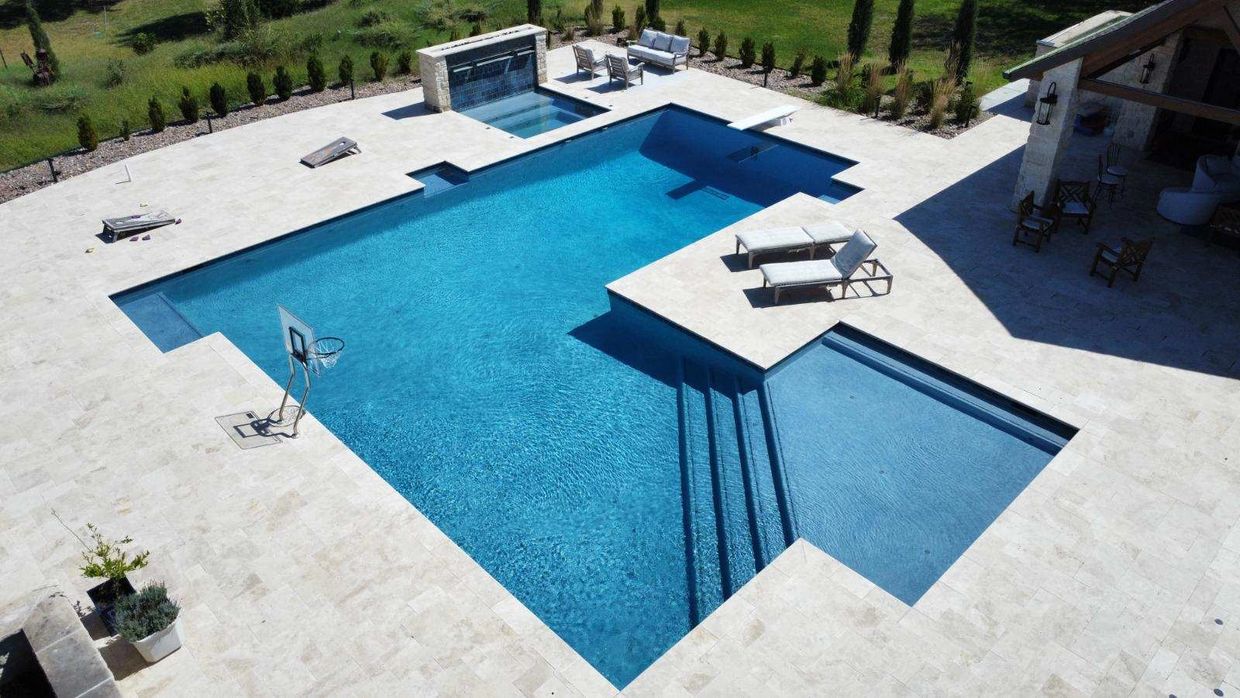 Gunite custom pools surrounded by lounge chairs and lush landscaping