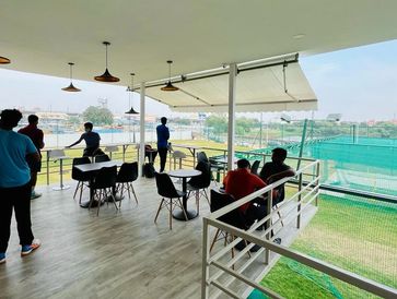 People observing a cricket practice from a terrace.