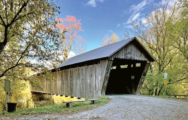 Old wooden covered bridge surrounded by trees.