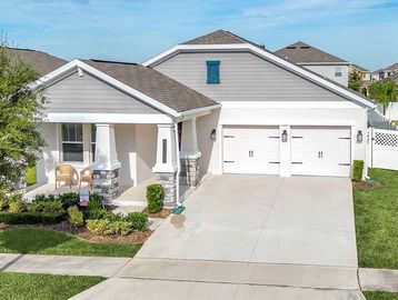 Grey and white single story home with covered front porch and two car garage. Well manicured lawn an