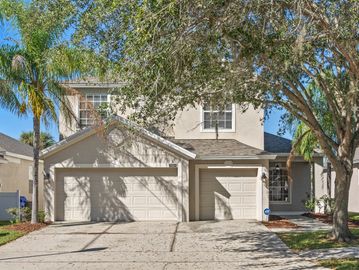 2 story white stucco home with front facing 3 car garage and a mature palm and oak tree.