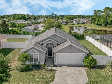 One story single family home with grey stucco and a white fence. Mature landscaping including grass.