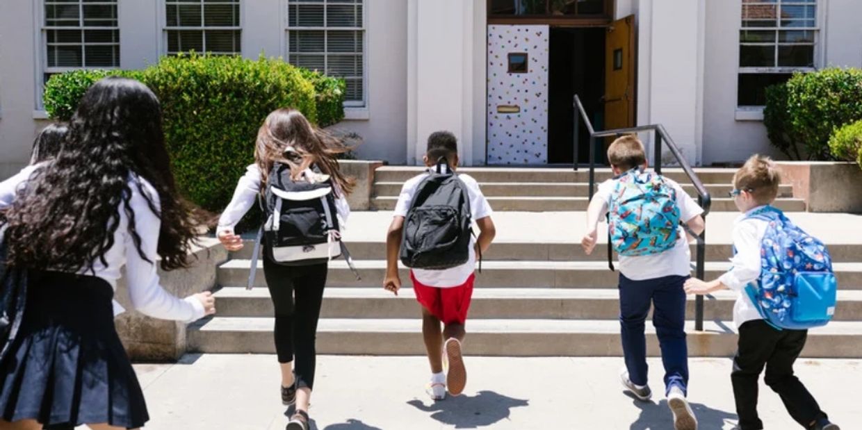 4 Children running into  the front doors of a school