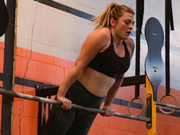 Woman performing a bar muscle-up at a gym.