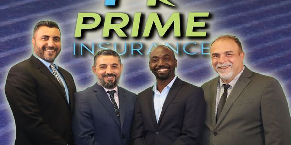 Four men in suits smiling in front of a Prime Insurance backdrop.