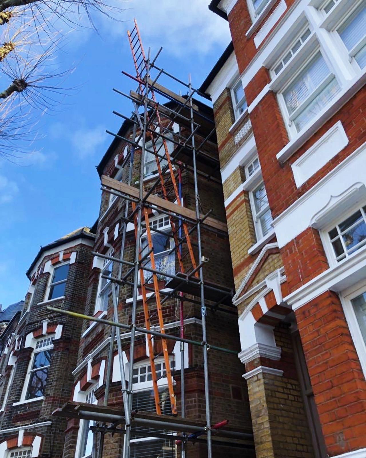Scaffolding set up on a brick residential building under a clear blue sky.