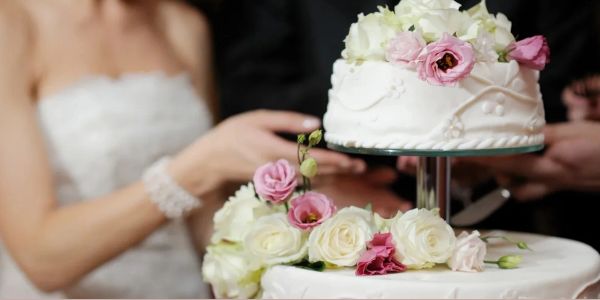 Wedding cake with flowers and blurred couple background.