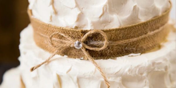 White textured cake with burlap ribbon and bow.