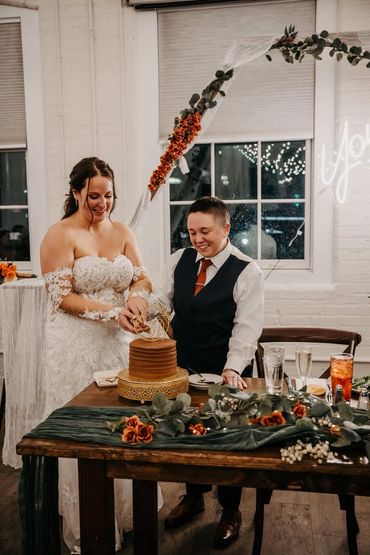 Couple cutting their wedding cake adorned with floral decorations.