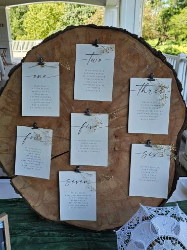 Wedding seating chart displayed on a large wooden slab with floral accents.