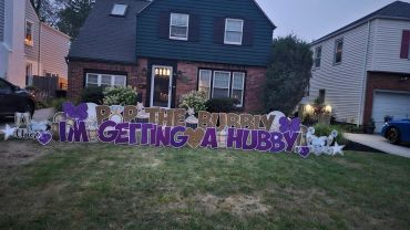 Yard sign announces engagement with text and decorations.