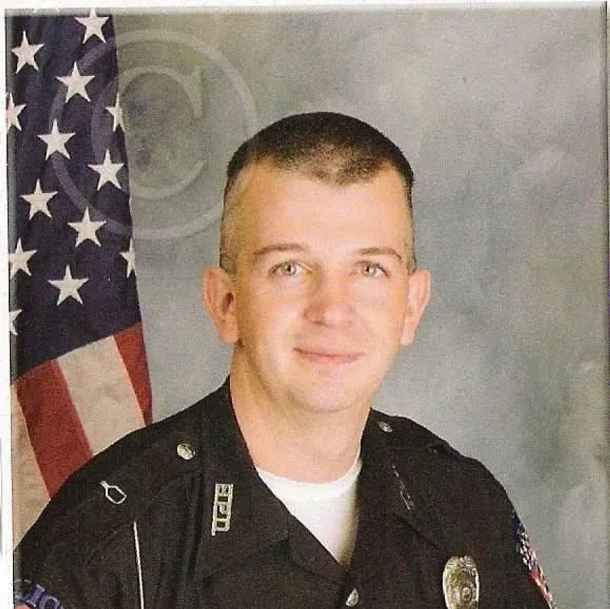 Portrait of a smiling police officer in uniform with American flag background.