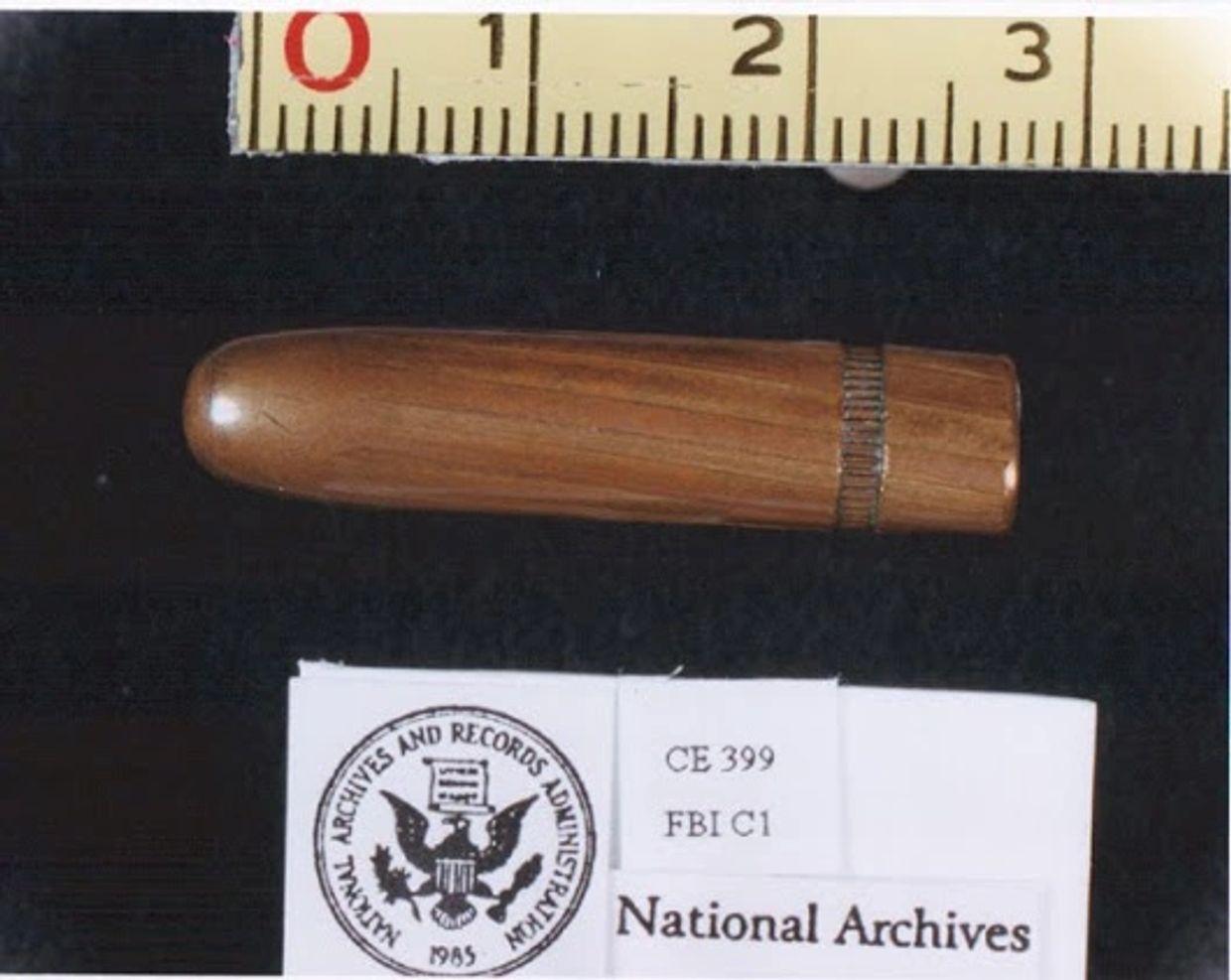 Wooden bullet displayed with a ruler and National Archives label.