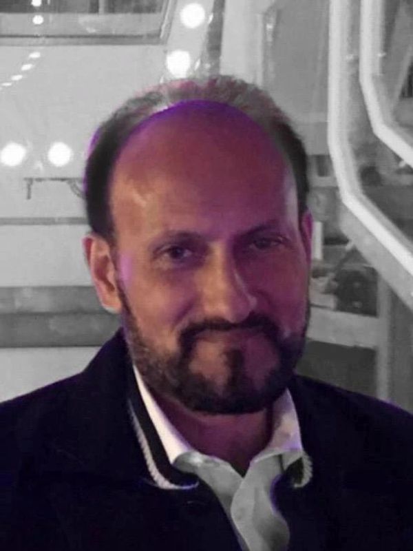 A man smiling with a beard and mustache.