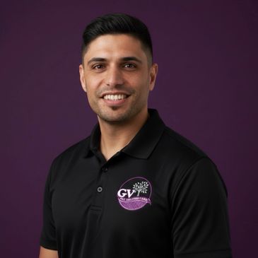 Smiling man in black polo shirt with logo on purple background.