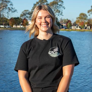 Young woman smiling by the water on a sunny day.