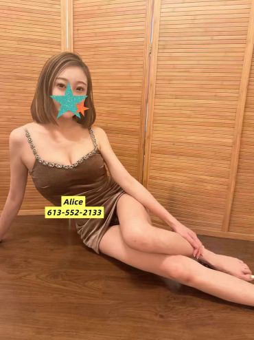 Woman in a brown dress sitting on a wooden floor with a wooden backdrop.