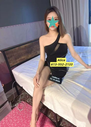 Woman in a black dress sitting on a bed in a room.